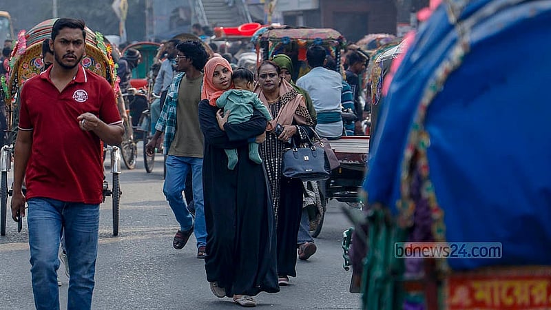 A woman carrying a child walks through the Science Laboratory intersection during the blockade on Thursday, Jan 15, 2026. Photo: Mahmud Zaman Ovi