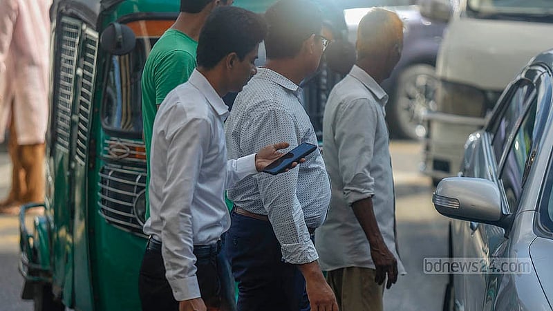 In Dhaka’s Karwan Bazar, a man walks in the middle of the road with his eyes on his phone screen, oblivious to a speeding vehicle behind him. Photo: Mahmud Zaman Ovi