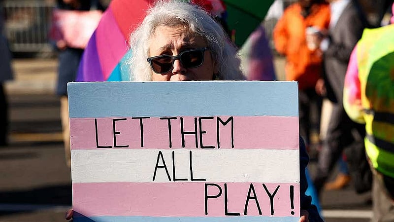A transgender rights supporter holds a placard while demonstrating on the day justices are expected to hear oral arguments in two cases concerning efforts to enforce Republican-backed state laws banning transgender athletes from female sports teams at public schools, outside the US Supreme Court in Washington, DC, Jan 13, 2026. REUTERS