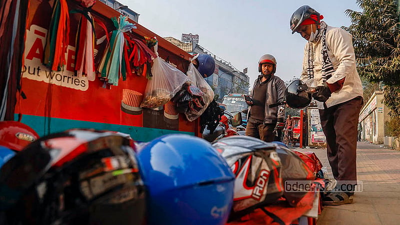 A motorcyclist stops to examine helmets at a footpath stall at the Science Lab intersection in Dhaka. Photo: Mahmud Zaman Ovi