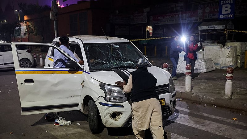 People push a damaged vehicle at the site of an explosion in the old quarters of Delhi, India, Nov 10, 2025.