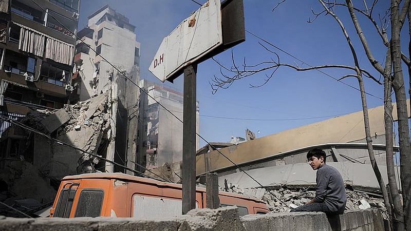 A boy sits on a wall near debris at the site of an Israeli strike, following an escalation between Hezbollah and Israel amid the US-Israeli conflict with Iran, Zuqaq al-Blat district in central Beirut, Lebanon, Mar 18, 2026. REUTERS/Khalil Ashawi