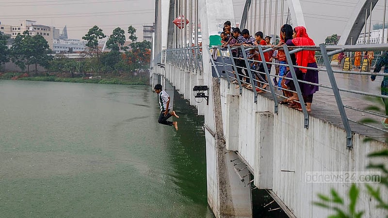 A child dives into the green and polluted waters of a lake in Hatirjheel amid the rain on Thursday, May 1, 2025. Photo: Mahmud Zaman Ovi