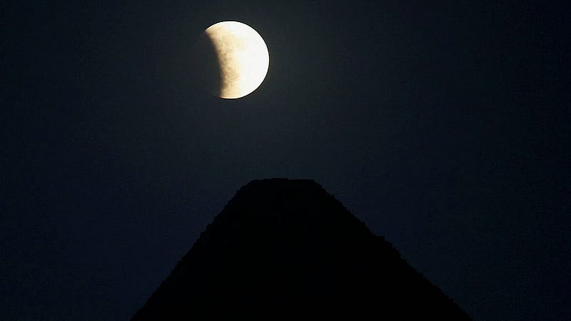 The moon appears during a lunar eclipse in the sky, behind the Pyramids of Giza, in Cairo, Egypt September 7, 2025. Photo: Reuters