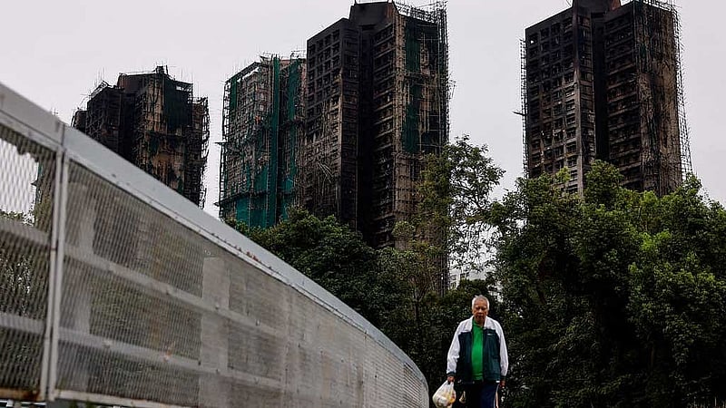 An elderly man walks next to burned buildings of the Wang Fuk Court housing complex after the deadly fire, in Tai Po, Hong Kong, China, Nov 30, 2025. REUTERS/Maxim Shemetov