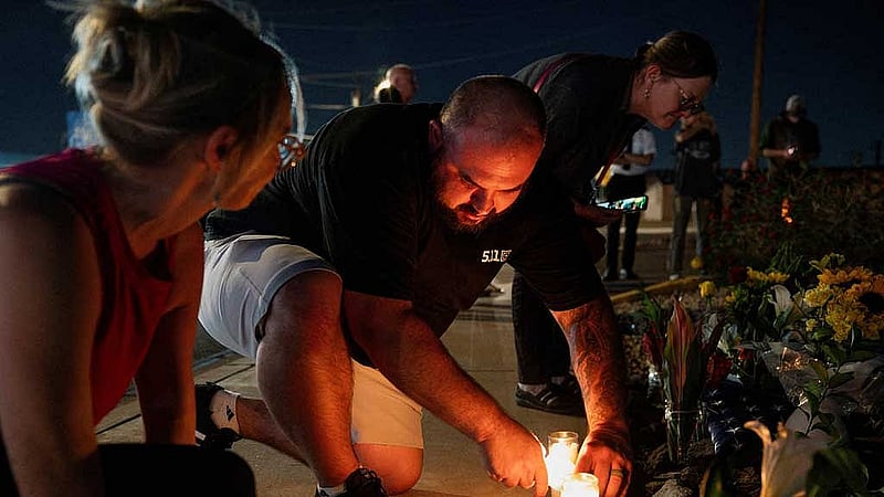 Phil McGee lights a candle at a makeshift memorial, to show support to slain conservative activist Charlie Kirk, outside the mortuary where Kirk's body was delivered, in Phoenix, Arizona, US, September 11, 2025, one day after Kirk was fatally shot during an event at Utah Valley University. REUTERS