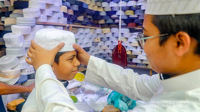 A customer tries on a skull cap at a shop outside the Baitul Mukarram Mosque in Dhaka. Photo: Abdullah Al Momin