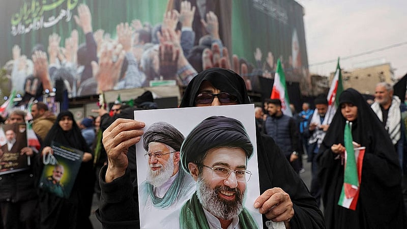 A woman holds an image of Iran's new supreme leader, Mojtaba Khamenei, alongside late Iranian Supreme Leader Ayatollah Ali Khamenei, during a funeral ceremony for the Iranian military commanders who were killed in strikes, amid the U.S.-Israeli conflict with Iran, in Tehran, Iran, March 11, 2026. Photo: Reuters