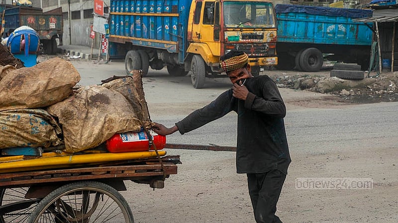 A man is trying to save his face while pushing a goods-laden vehicle from behind on the Dhaka-Narayanganj highway.