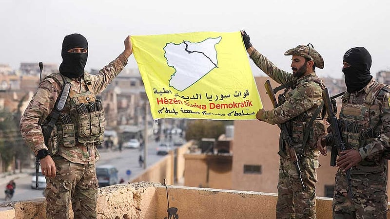 Members of the Kurdish-led Syrian Democratic Forces (SDF) hold a flag in the divided city of Deir al-Zor, Syria December 7, 2024. REUTERS