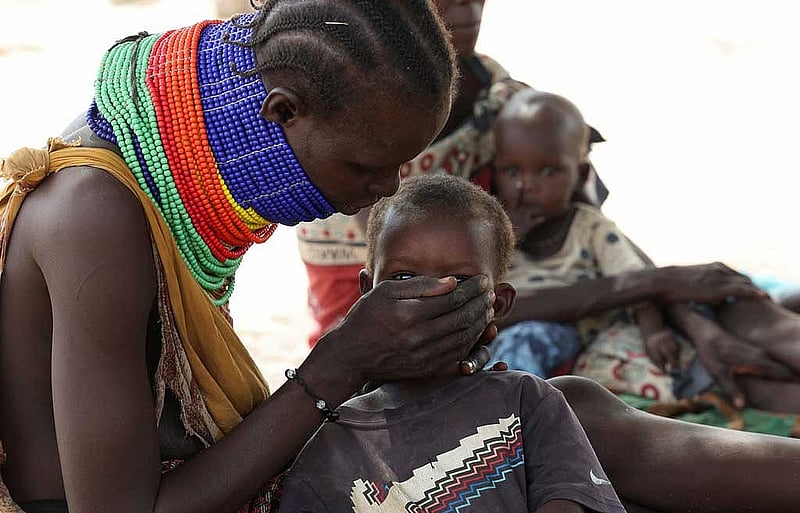 A Turkana woman sits with her child as they wait for malnutrition screening in Lomolem village, Turkana County, Kenya, Oct 29, 2025. REUTERS/Monicah Mwangi