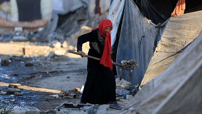 A Palestinian woman cleans an area next to tents, amid a ceasefire between Israel and Hamas, in Gaza City, Oct 14, 2025. REUTERS