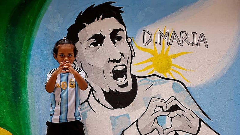 A young girl wearing an Argentine jersey displays a heart sign next to a mural depicting Argentine soccer player Angel Di Maria, ahead of the 2026 FIFA World Cup, in Dhaka, Bangladesh, Jun 9, 2026. REUTERS/Mohammad Ponir Hossain