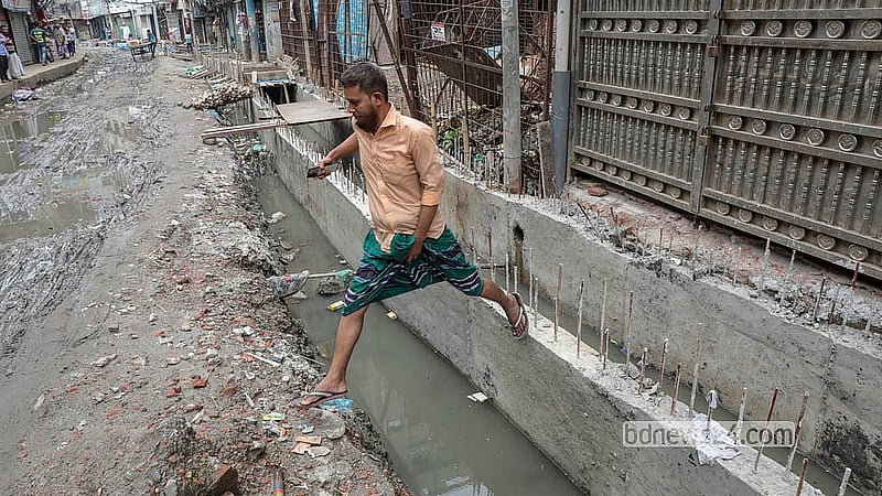 Residents navigate hazardous conditions as slow-moving drainage repairs continue along North Jurain Pipe Road in Shyampur. Photo: Abdullah Al Momin