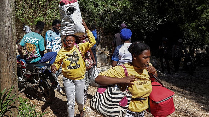 People carry their belongings as they flee their homes after a fatal overnight raid by an armed gang, on the outskirts of Port-au-Prince, in Kenscoff, Haiti, Aug 24, 2026. REUTERS/Patrice Noel
