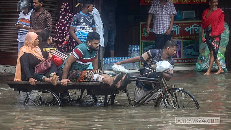 A patient heads to hospital on a rickshaw-van through waist-deep floodwater on the Arambagh road on Sunday, Jul 12, 2026.  Photo: Abdullah Al Momin