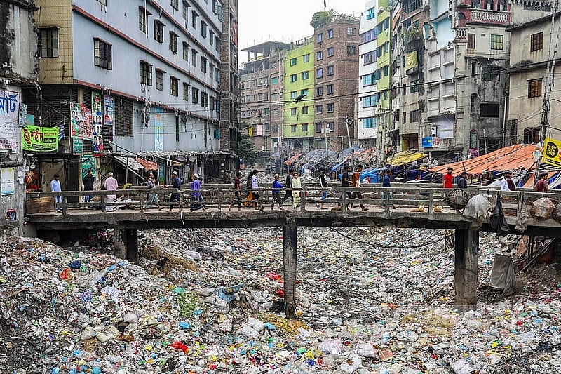 A stretch of Keraniganj’s Shubhadhya Canal lies buried beneath plastic waste, with people crossing the culvert above. File photo
