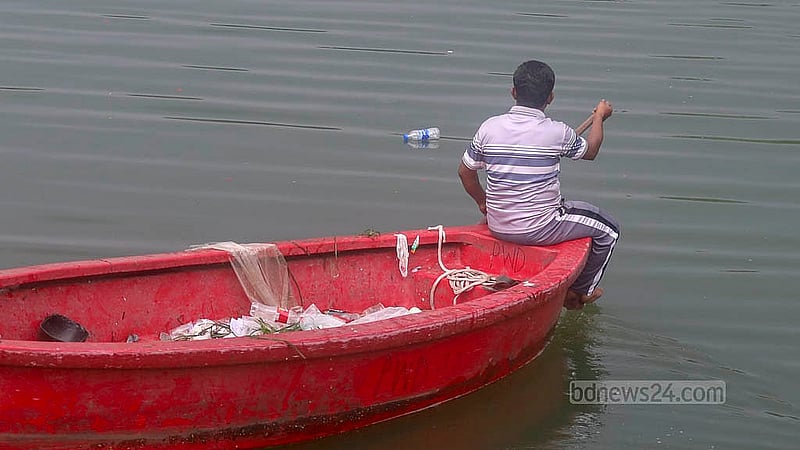 Thousands of people visit the Crescent Lake at the national parliament building every day. A man in a boat cleans up the waste they throw away. Photo: Abdullah Al Momin