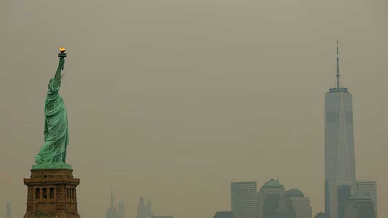 The Statue of Liberty in Jersey City, New Jersey, and the One World Trade Center tower in New York City are seen through a cover of wildfire smoke from New York Harbor, US, Jul 16, 2026. REUTERS