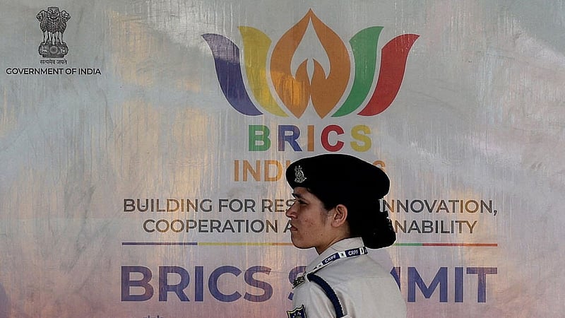 A member of the Central Reserve Police Force (CRPF) stands in front of a hoarding displayed near Bharat Mandapam, the venue of the upcoming BRICS Summit in New Delhi, India, Sept 9, 2026. REUTERS