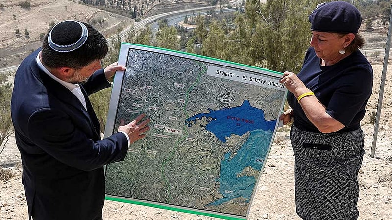 Israeli Finance Minister Bezalel Smotrich and a woman hold a map that shows the long-frozen E1 settlement scheme, that would split East Jerusalem from the occupied West Bank, on the day of a press conference near the Israeli settlement of Maale Adumim, in the Israeli-occupied West Bank, Aug 14, 2025. REUTERS