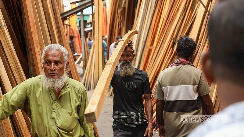 A worker carries sold timber logs on his shoulder towards their destination. Photo: Shamsul Haque Ripon