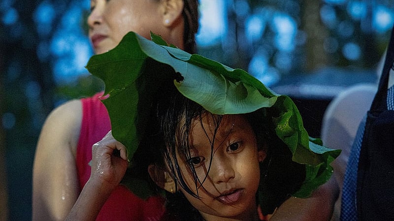 A girl uses leaves to protect herself from the rain as she prays at the Devghat mass burial site for the victims of the deadly flash floods and mudslides in Chitwan, Nepal, Sept 1, 2026. REUTERS/Adnan Abidi 
