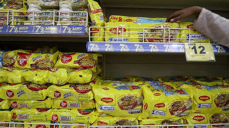 FILE PHOTO: A worker arranges packets of Nestle's Maggi noodles next to Reliance's Snac tac noodles on a shelf inside a Reliance supermarket in Mumbai, India, Mar 16, 2021. REUTERS