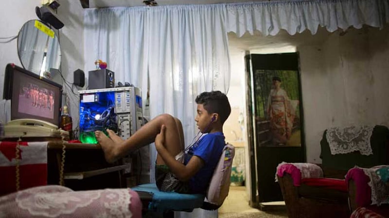 Kevin Lachaise, 8, watches a recorded TV show through the screen of a computer at
the living room of his home in downtown Havana Feb 10, 2015. REUTERS/Alexandre
Meneghini