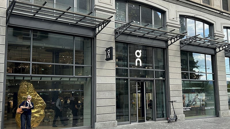 A woman stands in front of the storefront of an On retail shop in Zurich, Switzerland September 18, 2026. Picture taken with a mobile phone. REUTERS