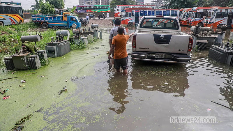 People wade through knee-deep water as they leave the DPDC office in Jatrabari’s Matuail.  Photo: Abdullah Al Momin