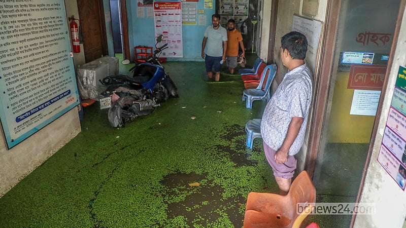 People wade through knee-deep water as they leave the DPDC office in Jatrabari’s Matuail.  Photo: Abdullah Al Momin