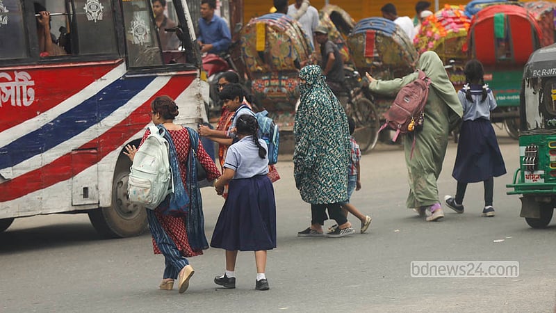 A parent raises a hand to cross in front of moving motorcycles and cars despite a footbridge being available at Malibagh intersection. Photo: Shamsul Haque Ripon