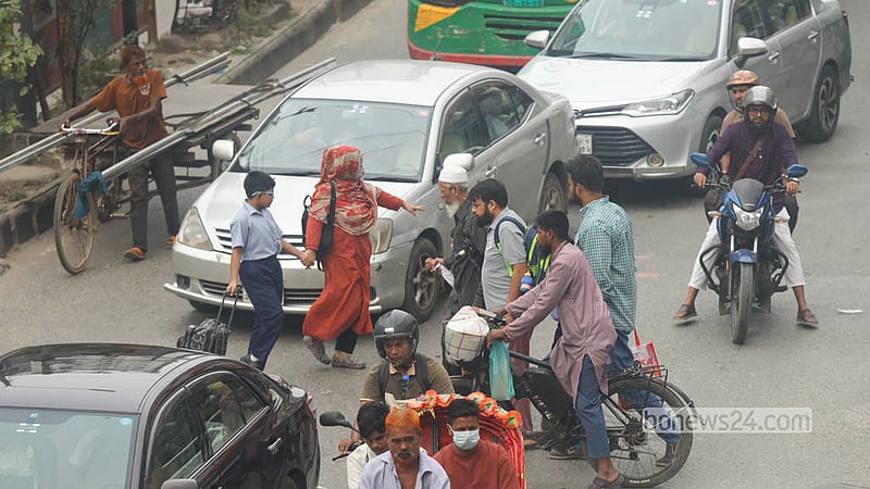 A parent slows traffic while crossing the busy road at Malibagh with a child. Photo: Shamsul Haque Ripon