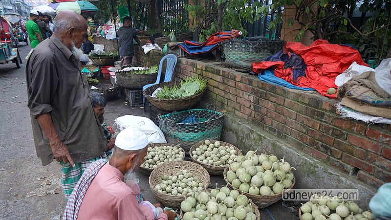 Traders wait for wholesale buyers beside baskets piled high with wood apples at a Shyambazar fruit depot. Photo: Shamsul Haque Ripon