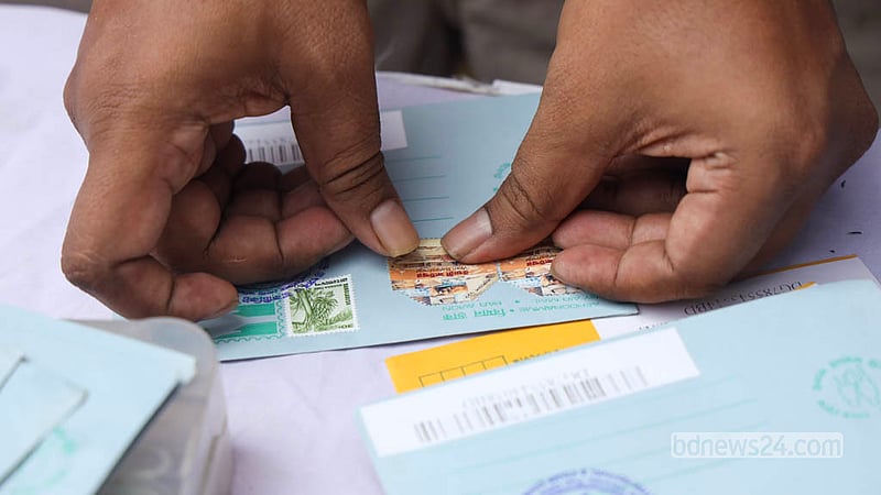 A visitor affixes a postage stamp to an envelope at the Letter Festival and Postage Stamp Exhibition at Dhaka University’s TSC on Monday, Oct 12, 2026. Photo: Shamsul Haque Ripon