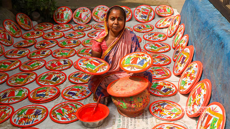 A woman potter holds a traditional Lakshmi sara, its surface adorned with intricate folk designs in Sirajdikhan’s Palpara in Munshiganj.  Photo: Shamsul Haque Ripon
