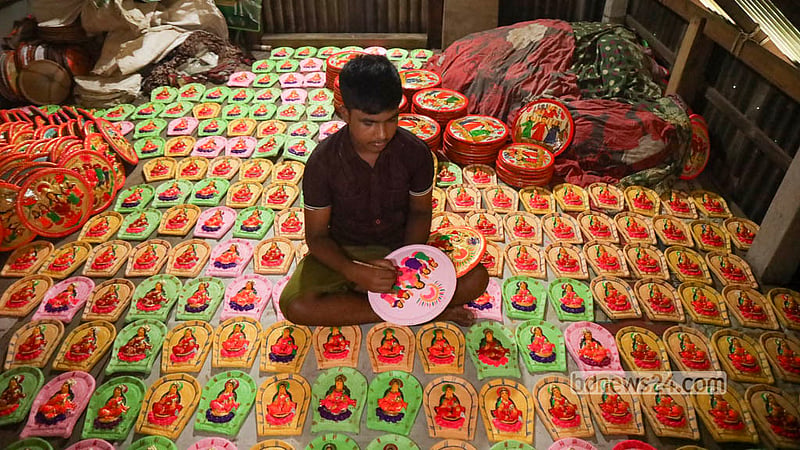 A young potter carefully paints rows of Lakshmi sara and clay idols inside a home in Sirajdikhan.  Photo: Shamsul Haque Ripon