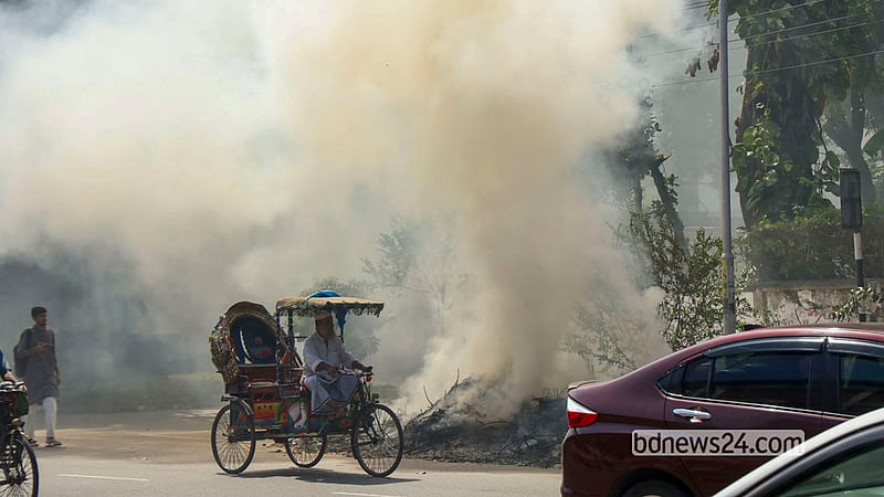 The road between the TSC and Rokeya Hall on the Dhaka University campus is shrouded in the smoke of burning garbage on Tuesday, Oct 13, 2026. When the campus is cleaned, leaves and garbage are burnt along the road.  Photo: Shamsul Haque Ripon