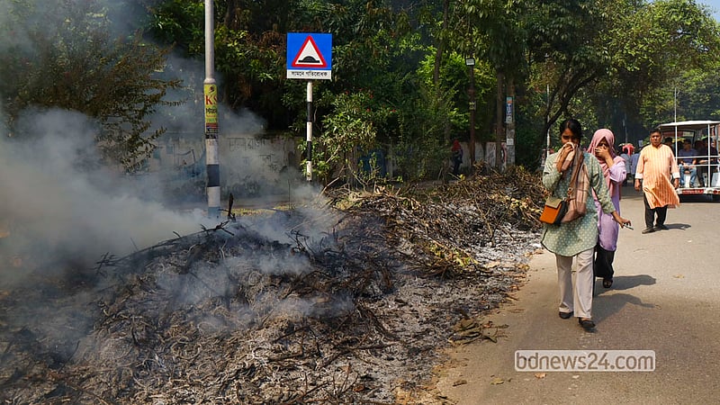 Students hold their noses while shrouded in the smoke of burning garbage on the road in front of the TSC on the Dhaka University campus on Tuesday, Oct 13, 2026. Photo: Shamsul Haque Ripon