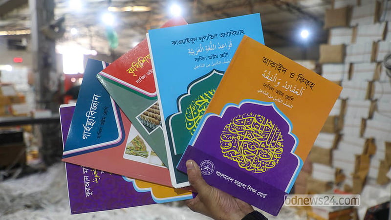A worker holds up a freshly printed secondary-level textbook for the 2027 academic year at a printing press in Dhaka’s Matuail. Photo: Abdullah Al Momin
