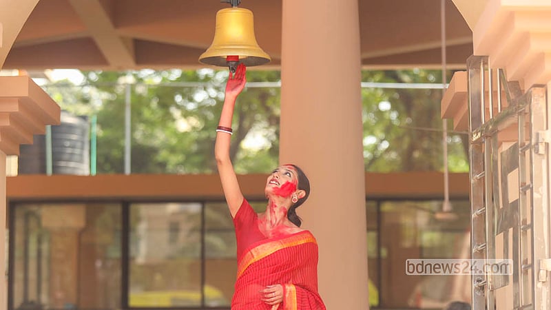 A woman in a red saree, her face smeared with vermilion, rings a bell during Sindoor Khela at Dhakeshwari National Temple on Bijoya Dashami. Photo: Shamsul Haque Ripon