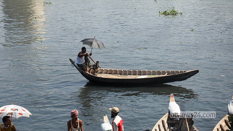 A boatman waiting to ferry passengers across the Buriganga River in Dhaka uses an umbrella to escape the heat. Photo: Shamsul Haque Ripon