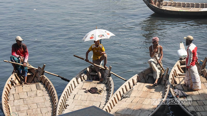 A boatman waiting to ferry passengers across the Buriganga River in Dhaka uses an umbrella to escape the heat. Photo: Shamsul Haque Ripon