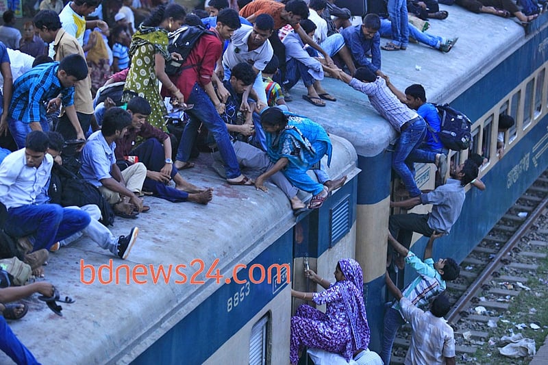 People ride on the rooftop of a train at Airport Railway station in Dhaka to reach their homes on Monday ahead of Eid-ul-Azha.