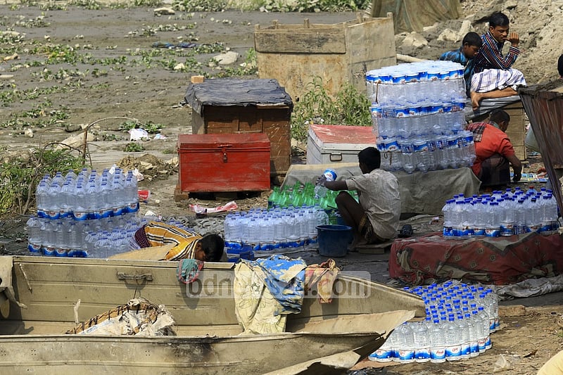 Used water bottles are being washed to refill water from washer line near Dhaka's Sadarghat area.