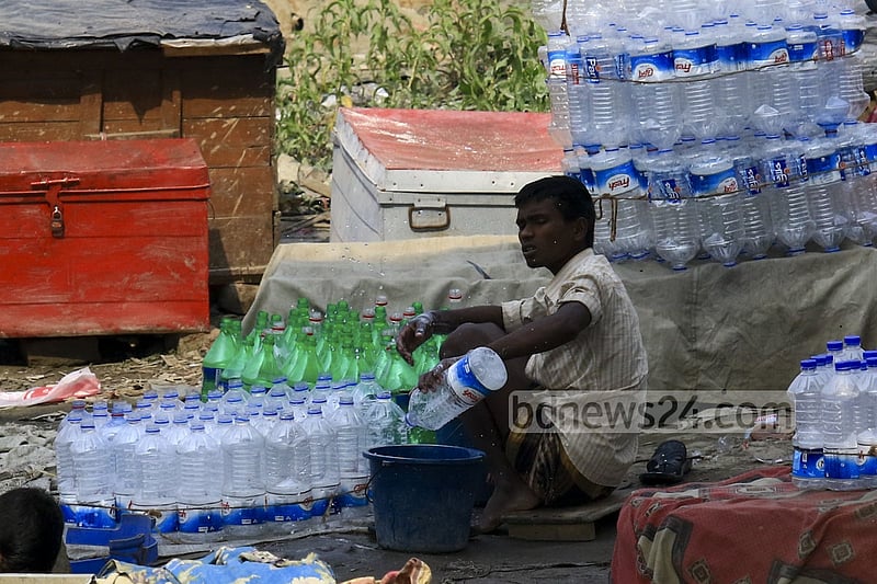 Used water bottles are being washed to refill water from washer line near Dhaka's Sadarghat area.