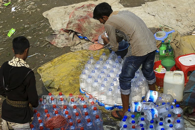 Used water bottles are being washed to refill water from washer line near Dhaka's Sadarghat area.