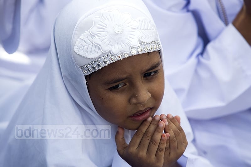 A young girl raises her hands for Eid prayers at the National Eidgah on Monday. Photo: mostafigur rahman