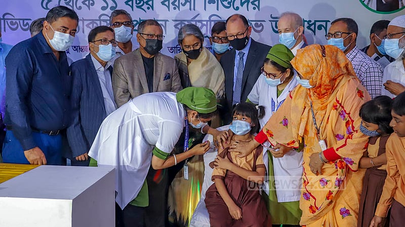 শিশুদের পরীক্ষামূলক টিকার প্রথমটি পেয়েছে তৃতীয় শ্রেণি পড়ুয়া নিধি নন্দিনী কুণ্ডু। বৃহস্পতিবার বঙ্গবন্ধু শেখ মুজিবুর রহমান আন্তর্জাতিক সম্মেলন কেন্দ্রে ৫ থেকে ১১ বছর বয়সী শিশুদের দেওয়া হয় বিশেষভাবে তৈরি ফাইজারের টিকার প্রথম ডোজ। এদিন ঢাকার শেরে বাংলা নগর আবুল বাশার সরকারি প্রাথমিক বিদ্যালয়ের দ্বিতীয় থেকে পঞ্চম শ্রেণির ১৭ শিক্ষার্থীকে এ টিকা দেওয়া হয়। ছবি: আসিফ মাহমুদ অভি
